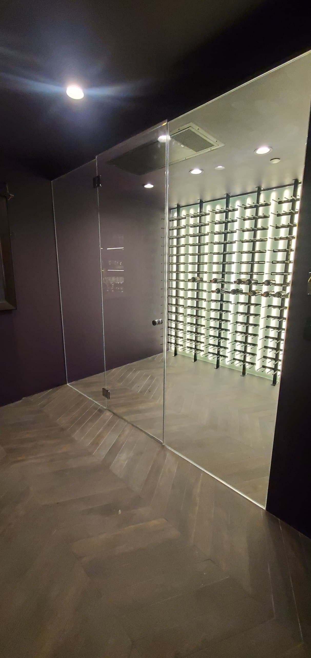 Frameless glass wine cellar enclosure with backlit racking