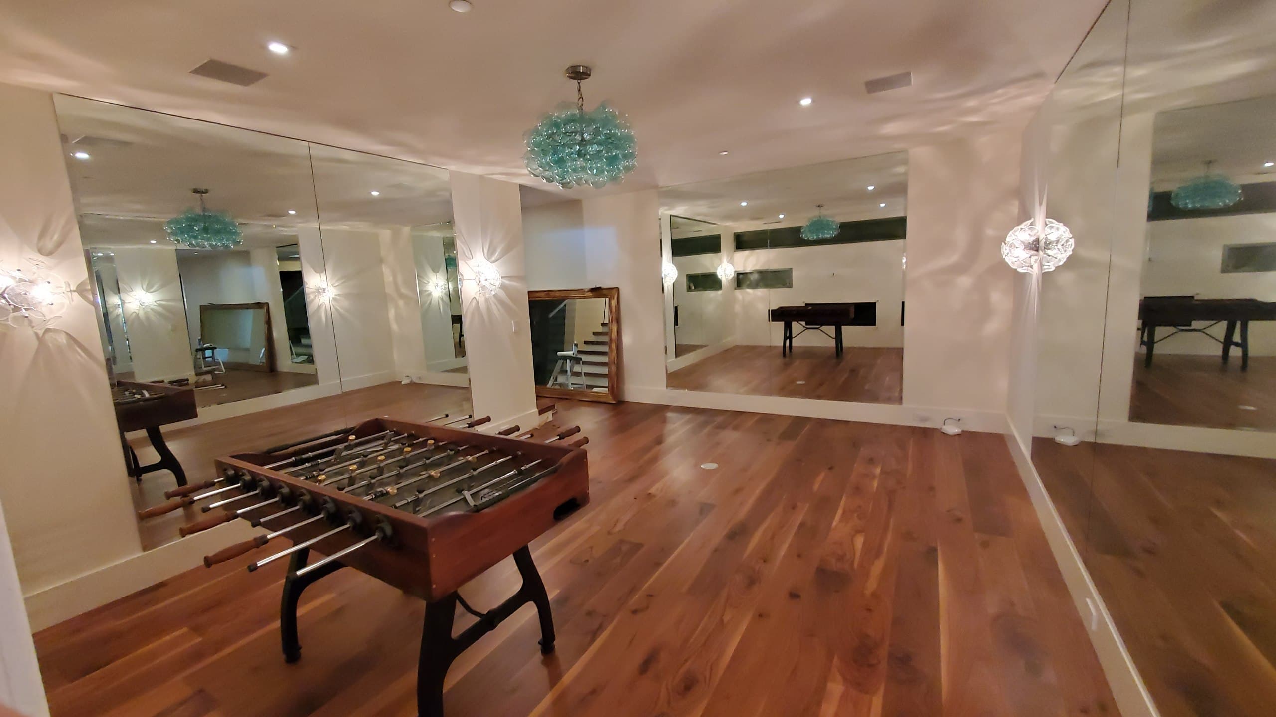 Floor-to-ceiling mirror walls in a residential game room with wood floors